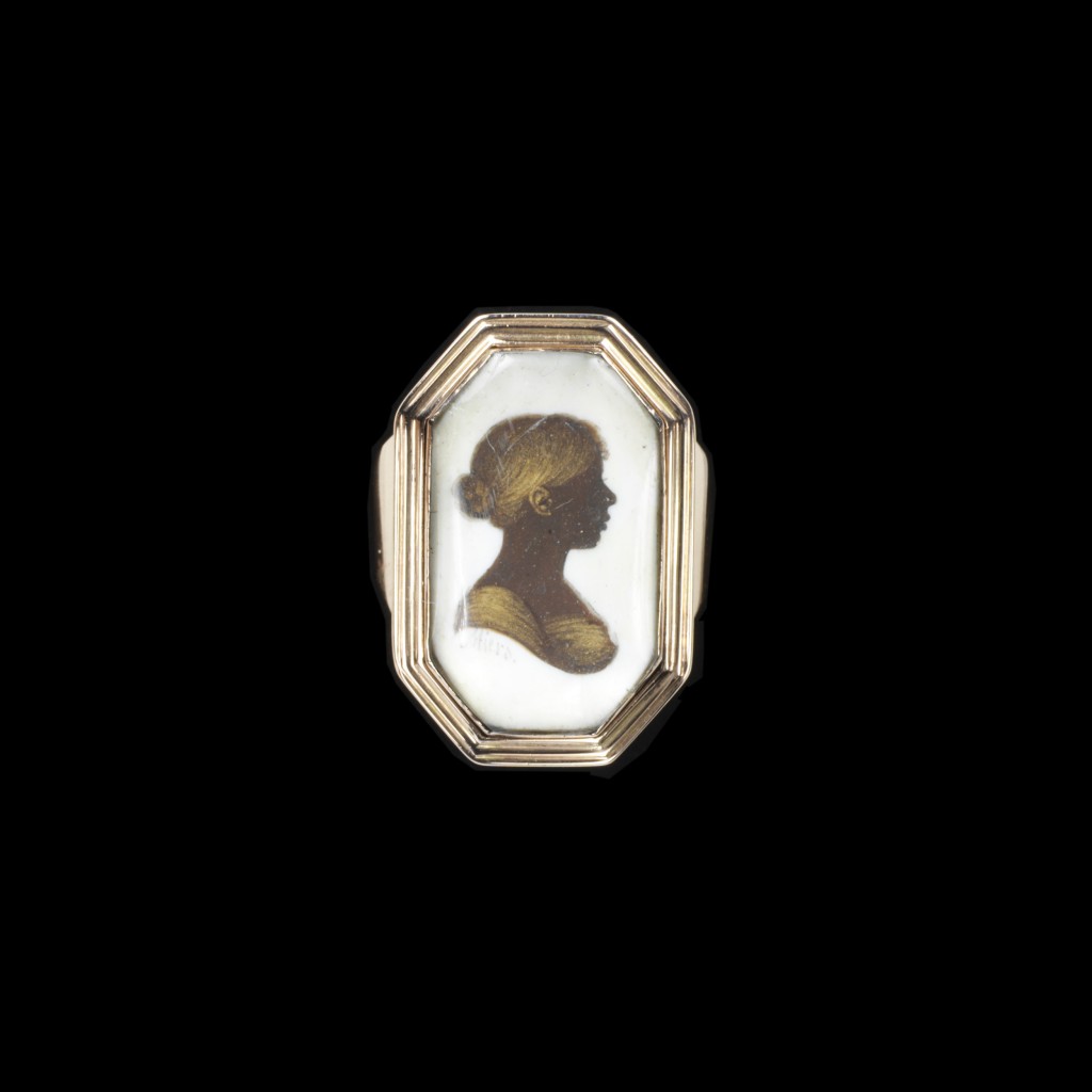 Gold ring with hexagonal bezel set with a silhouette of a young girl.