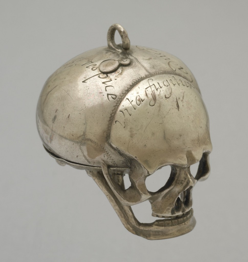 SILVER CASED VERGE WATCH IN THE FORM OF A HUMAN SKULL. . MOVEMENT FRAME: Full-plate with circular gilt-brass plates and four baluster pillars. : MAINSPRING & SET-UP: Gilt-brass barrel with tangent-screw set-up mounted on the potence-plate. : FUSEE & STOP-WORK: Gilt-brass fusee with chain and English stop-work. : TRAIN: Four wheel train, the contrate wheel solid. : ESCAPEMENT & BALANCE: Verge escapement, the crown wheel running between riveted potence and counter-potence. There have been extensive alterations to both potence and counter-potence suggesting that the crown wheel is most likely to be a replacement. Verge and steel 2-arm balance not original. The pierced and engraved gilt-brass foliate balance cock is also a replacement. There are a number of vacant holes,both threaded and plain, in the potence-plate where it appears that the original balance cock was replaced by a balance bridge and balance spring. : DIAL & HAND: An engraved border on the front of the pillar-plate surrounds the pinned-on silver dial which has Roman hours I-XII, arrow-head half-hour marks and a quarter circle. The blued-steel hand is a replacement. : CASE: Silver case in the form of a human skull, the lower plate, including the lower jaw being hinged at the back. On top there is a cover for the winding hole. Silver hanging loop. There are inscriptions in various places on the outside of the skull. Movement hinged to case at XII.