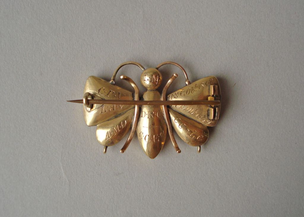 Gold brooch in the form of a butterfly, with seven plaited hair arrangements under glass, two for each wing and three for the body. The gold mounts with engraved decoration. The reverse inscribed with initials and the date 1839 and 1842.