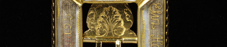 This mourning buckle contains panels of woven hair, decorated with an elaborate inscription in gold thread and a small enamelled skull, all set behind rock crystal. The inscription, partly in latin, tells us that the piece commemorates Elizabeth Harman who died on 11 April 1698, aged 27.