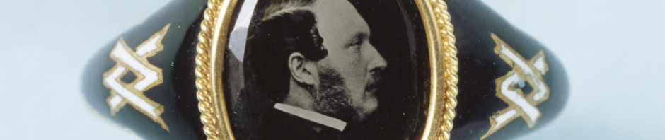 Memorial ring in gold and black enamel, the bezel containing a microphotograph, reversed, of the Prince Consort in 1861, which is attributed to J.J.E. Mayall. The cypher linking the initials 'V' and 'A' in white enamel is set into the shanks on either side of the bezel