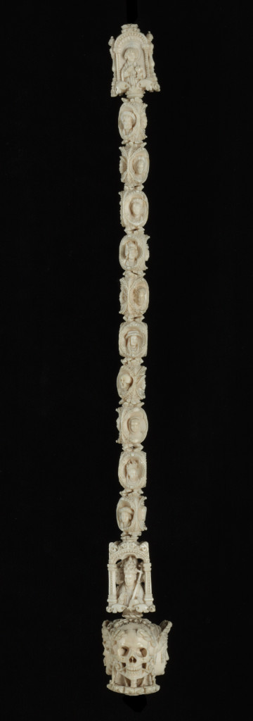 This is an ivory chaplet made in France or South Netherlands in about 1530. The beads are carved with figures of the Virgin Mary and St John the Evangelist, the joined heads of a man, woman and Death, and images of the Pope, kings and figures in aristocratic dress. The Italianate ornament in which these images are set is characteristic of the style considered fashionable by sophisticated French purchases of such luxury items around 1550. Considered all together the beads constitute a sculptural equivalent of the Office of the Dead found in contemporary Books of Hours, and indeed the extensive choice of figures, including the fool and what may be taken as members of the various ecclesiastical, courtly and professional hierarchies, echoes that found in the margins of Philippe Pigouchet's Book of Hours of the late 1490s. In the Late Middle Ages the chaplet was a vital and commonplace aid to keeping count of the repetition of prayers for both rich and poor. Often hung from the belt by a ring, it usually consisted of ten ‘ave’ (Hail Mary) beads with a larger ‘paternoster’ (Our Father) bead at the beginning or end and a terminal Crucifix. Chaplet beads were made in many materials, from humble plain wood to precious metals and ivory. The popularity of the rosary – the fullest form of repeated prayers – gave rise to the establishment of confraternities devoted to its use in the late fifteenth century, so that by the sixteenth century the production of intricate and costly chaplets was widespread. Chaplets often ended not with a cross but with a terminal pendant, and it is these larger beads which are usually the grandest. Most of them are connected with the notion of the memento mori, a constant reflection that human life is transient. The most common type of memento mori bead is that with conjoined heads: the skull, representing Death, is always present, and is either backed with a single bust or a pair of heads, male and female. The depiction of the skull often allowed the carver’s imagination full rein, with toads, worms and lizards crawling in and out of the mouth and eye sockets.