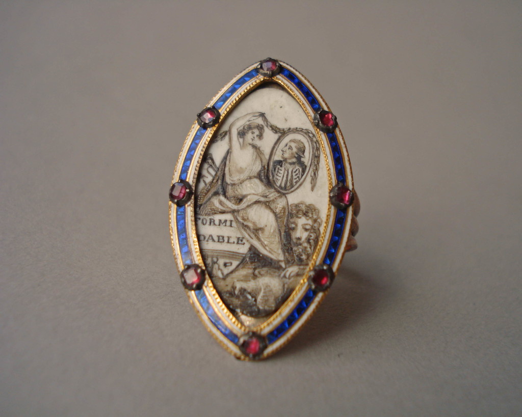 Mourning ring; gold; marquise bezel studded round border with garnets in settings over bands of blue and white enamel; contains figure of Britannia(?) sitting on stern of vessel on which is a name, and wreathing the picture of an admiral; lion at her feet with paw on dead dove. No maker's mark.