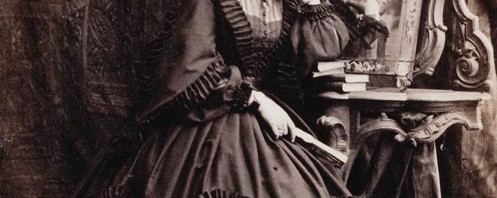 Photograph of Princess Alice, standing while resting her left elbow on some books piled on a console table with a mirror reflecting the left side of her head and her left hand. Princess Alice became engaged to Prince Louis of Hesse on 30 November 1860; their marriage took place in July 1862, having been postponed because of the death of the Prince Consort in December 1861. The Princess is wearing mourning in this photograph for her grandmother, the Duchess of Kent, who had died four months previously. Provenance Acquired by Queen Victoria