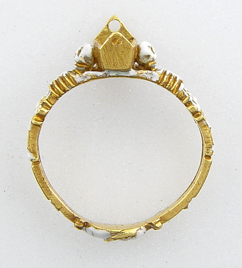 Mourning-ring; enamelled gold, the hoop enamelled white, in the form of two skeletons supporting a coffin-shaped bezel with moveable lid fastened with a pin and ornamented with a Maltese cross once enamelled red, on a black ground with hearts reserved in the metal, an enamelled cinquefoil at one end. Inside the coffin is a tiny white-enamelled skeleton. At the back of the bezel ares two clasped hands.