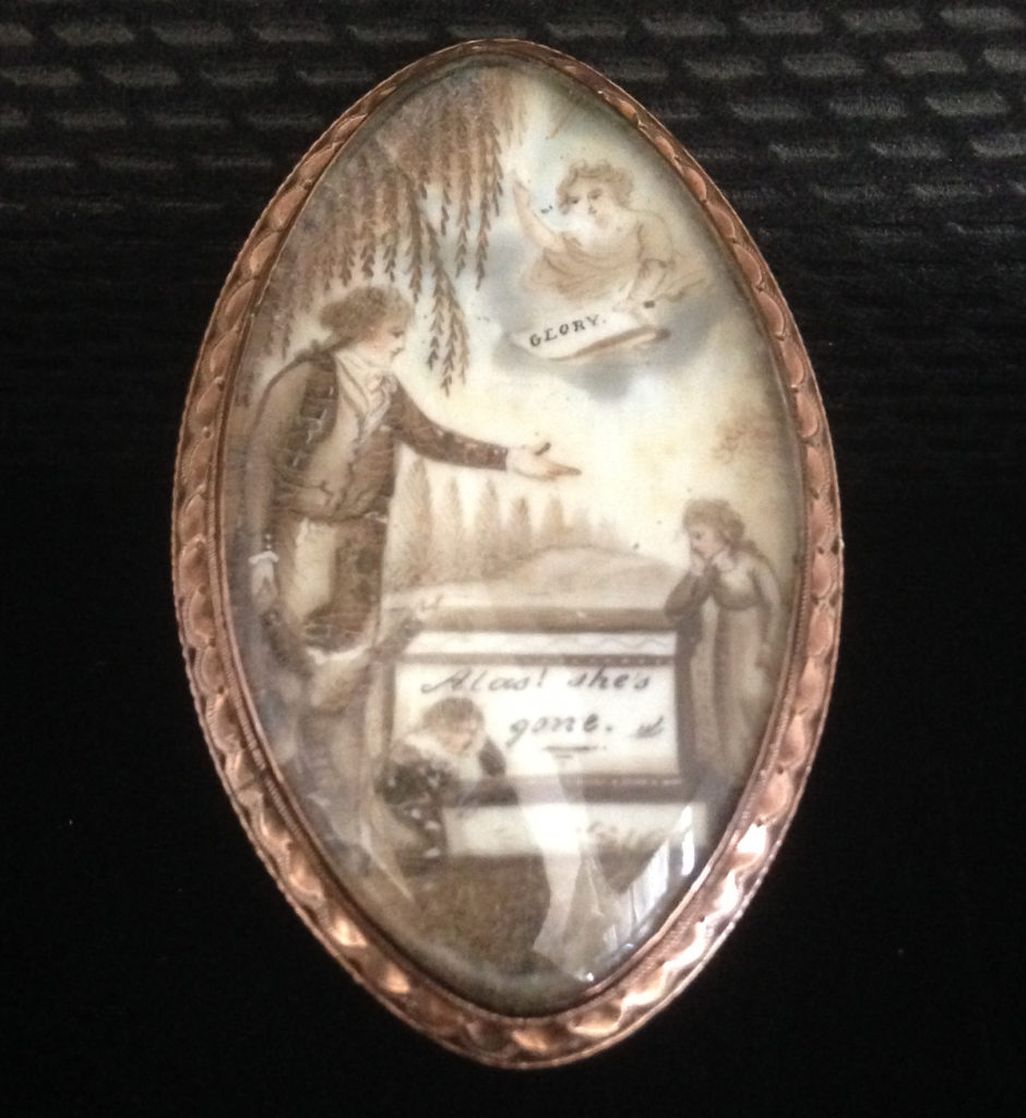 Neoclassical mourning jewel showing father and children next to a tomb inscribed 'Alas! She's gone'. In the Heavens is a cherub holding a sign stating 'GLORY'.