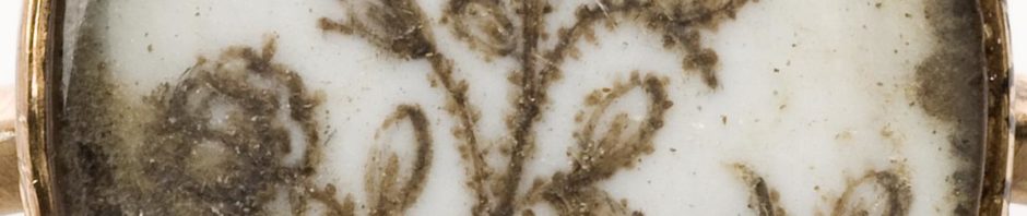 Gold memento mori ring, with oval setting which shows a flower and an inscription painted on a white background, beneath glass, possibly, glass, possibly 18th century. Detail view of flower and inscription on ring. White background. Wellcome collection at the Science Museum.