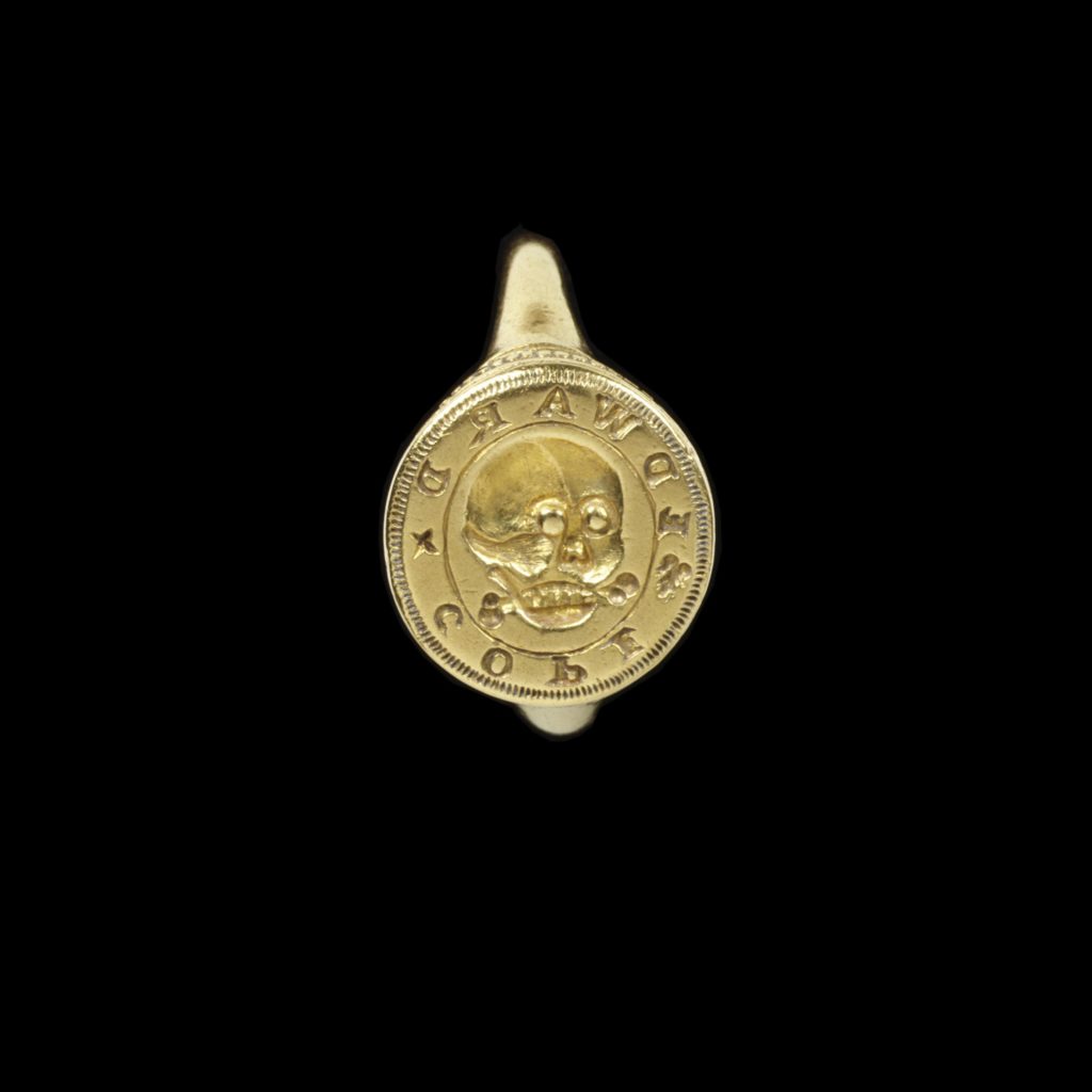 c.1600-1650. Gold signet ring, with a circular bezel engraved with a skull surrounded by the name 'EDWARDxCOPE', with behind a fragment of bone, presumably a talisman or relic. Courtesy V&A.