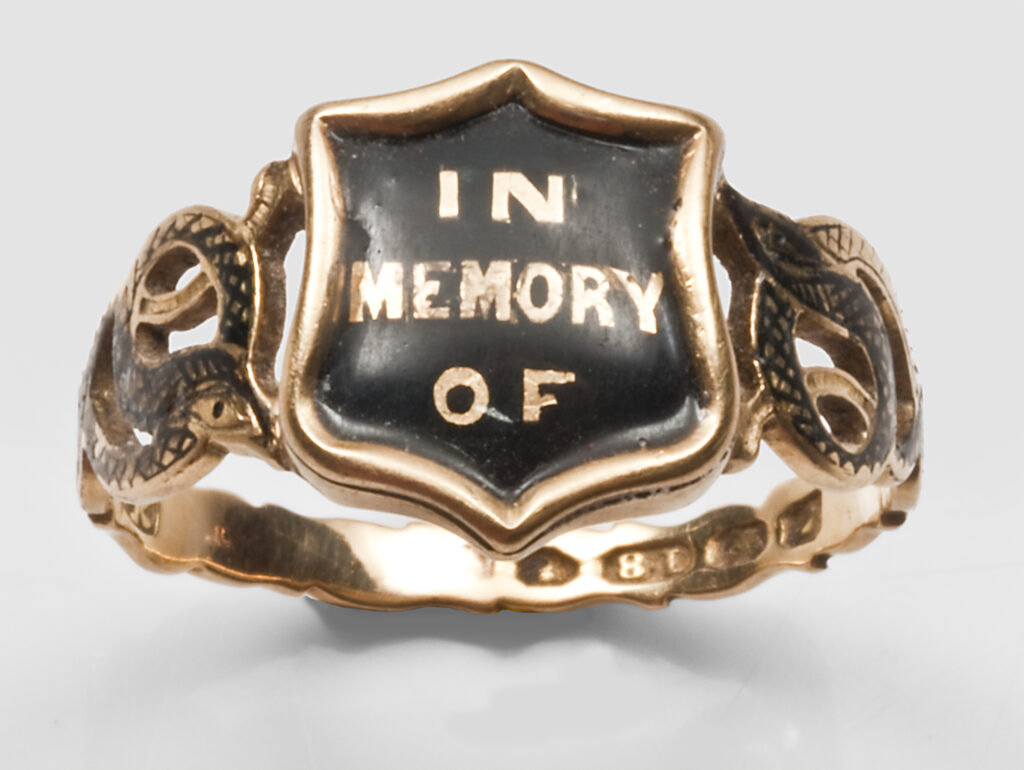 Mourning ring reading 'IN MEMORY OF' for Mary Ann Lewis who died in 1853. Her hair is underneath the bezel in a glass compartment. 